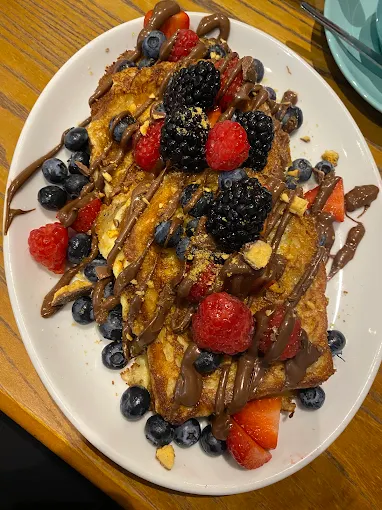Loaded french toast with chocolate drizzle, berries and nuts
